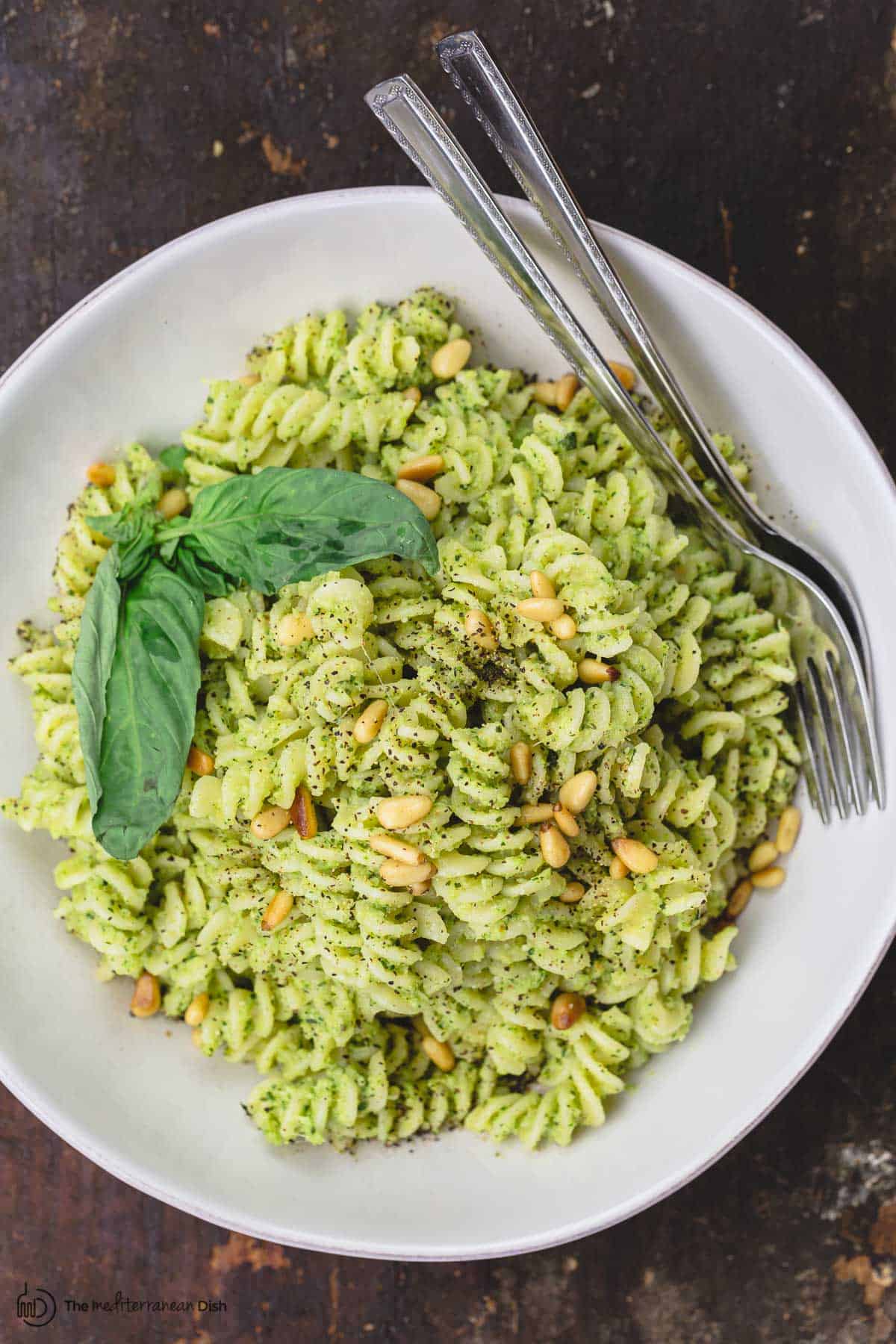 A bowl of broccoli pesto pasta with pine nuts and basil