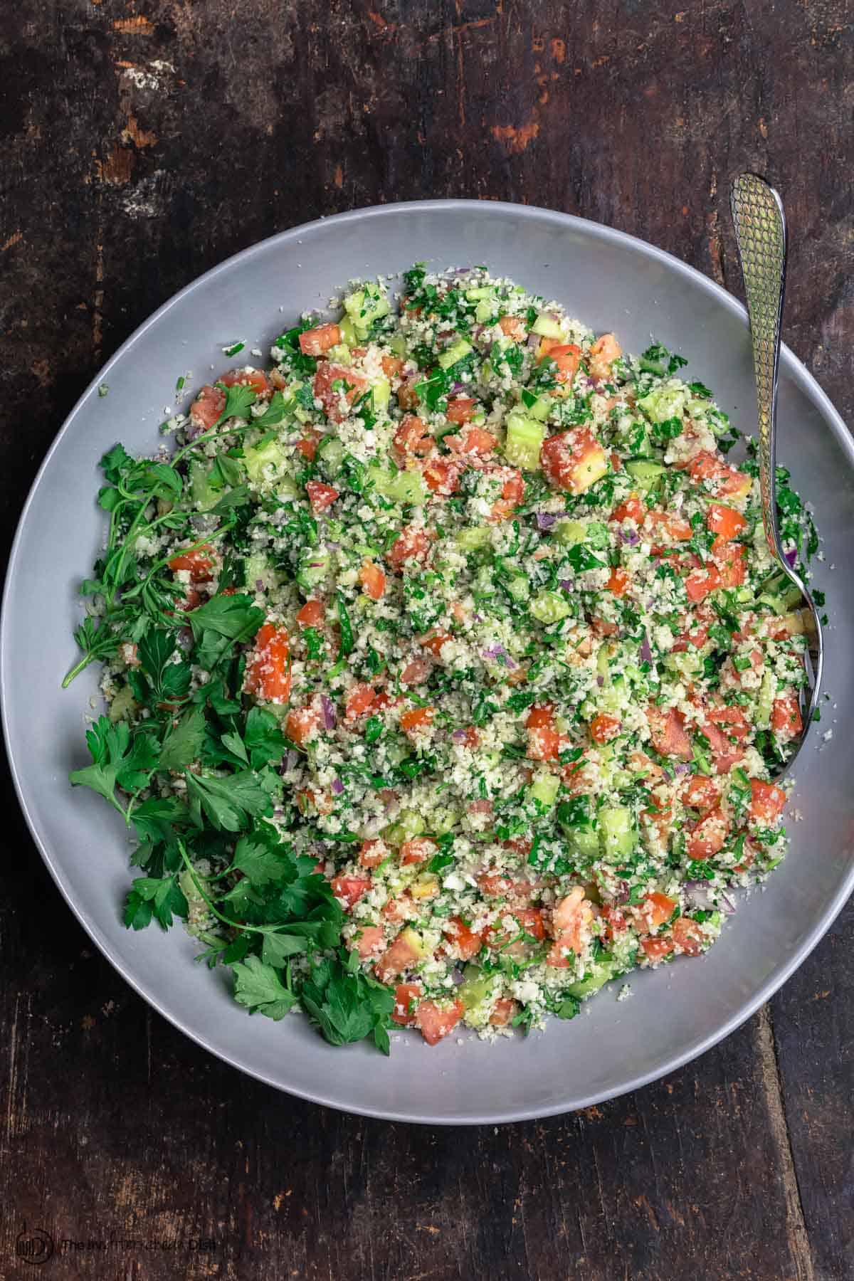 Mediterranean cauliflower salad with tomatoes, cucumbers, parsley and red onions, served in a large bowl