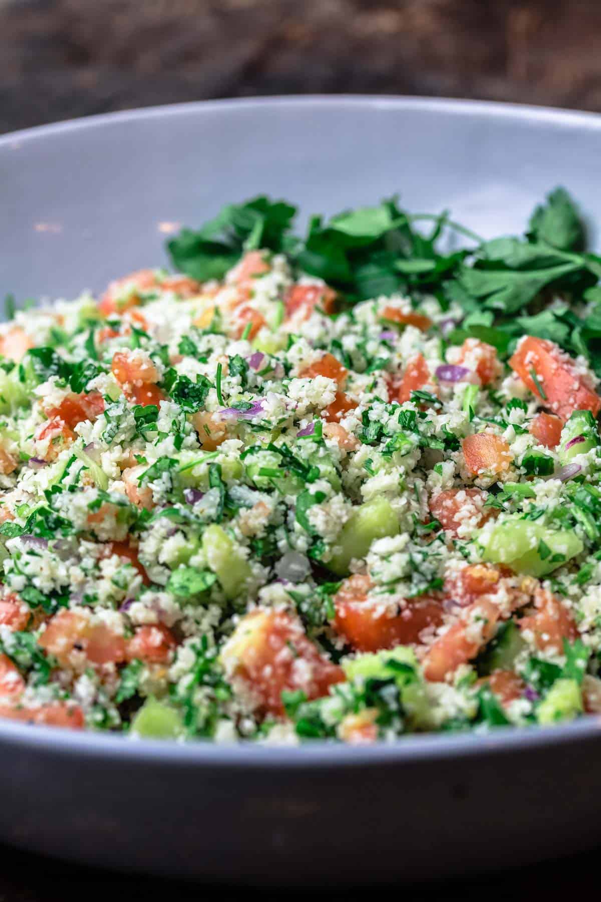 cauliflower salad in a large bowl with fresh parsley for garnish