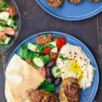 Two plates of chicken kofta patties with a side salad and hummus