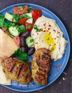 two chicken kofta with hummus, salad and pita on blue plate for serving
