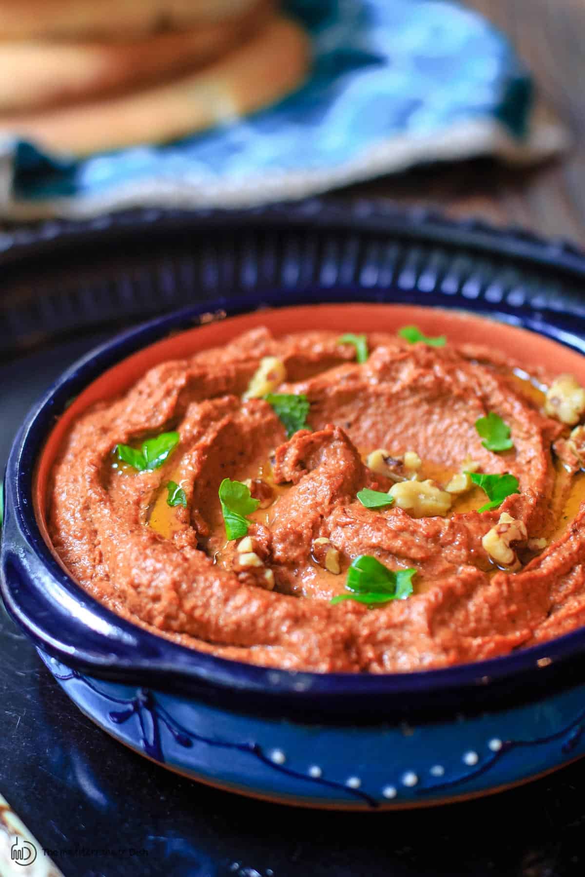 Muhammara in a bowl with a side of pita bread