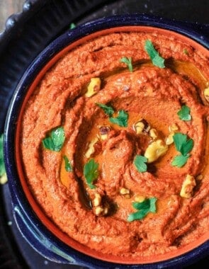Muhammara roasted red pepper and walnut dip in a bowl, topped with walnuts and parsley for garnish