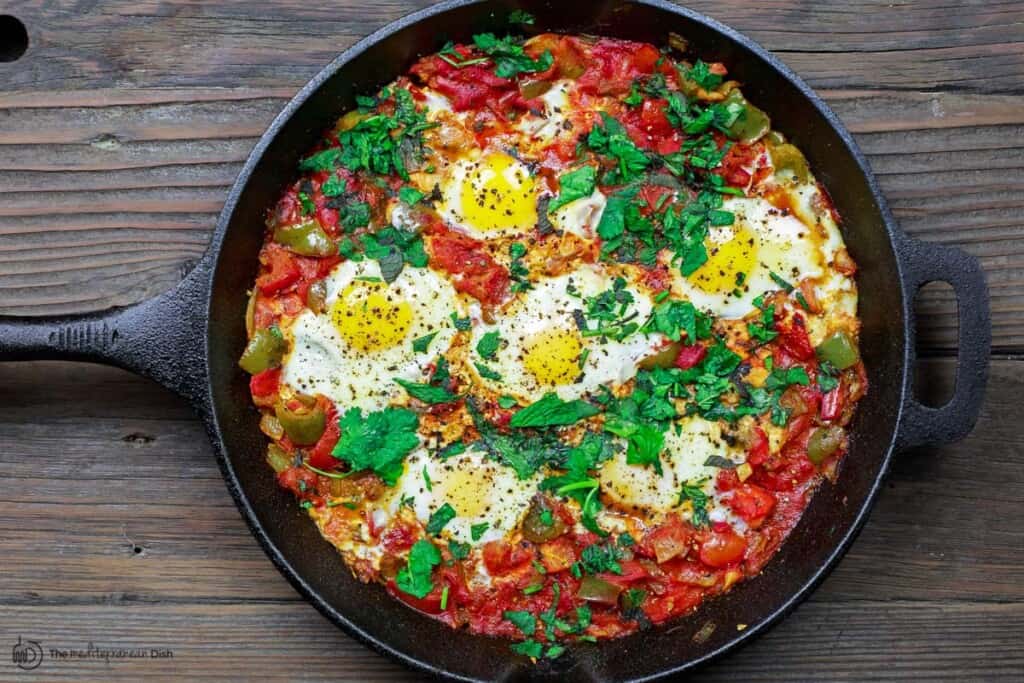 cooked shakshuka recipe with garnish of parsley and mint