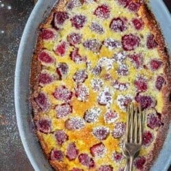 Rasbperry Claufotis in baking dish with a side of fresh berries