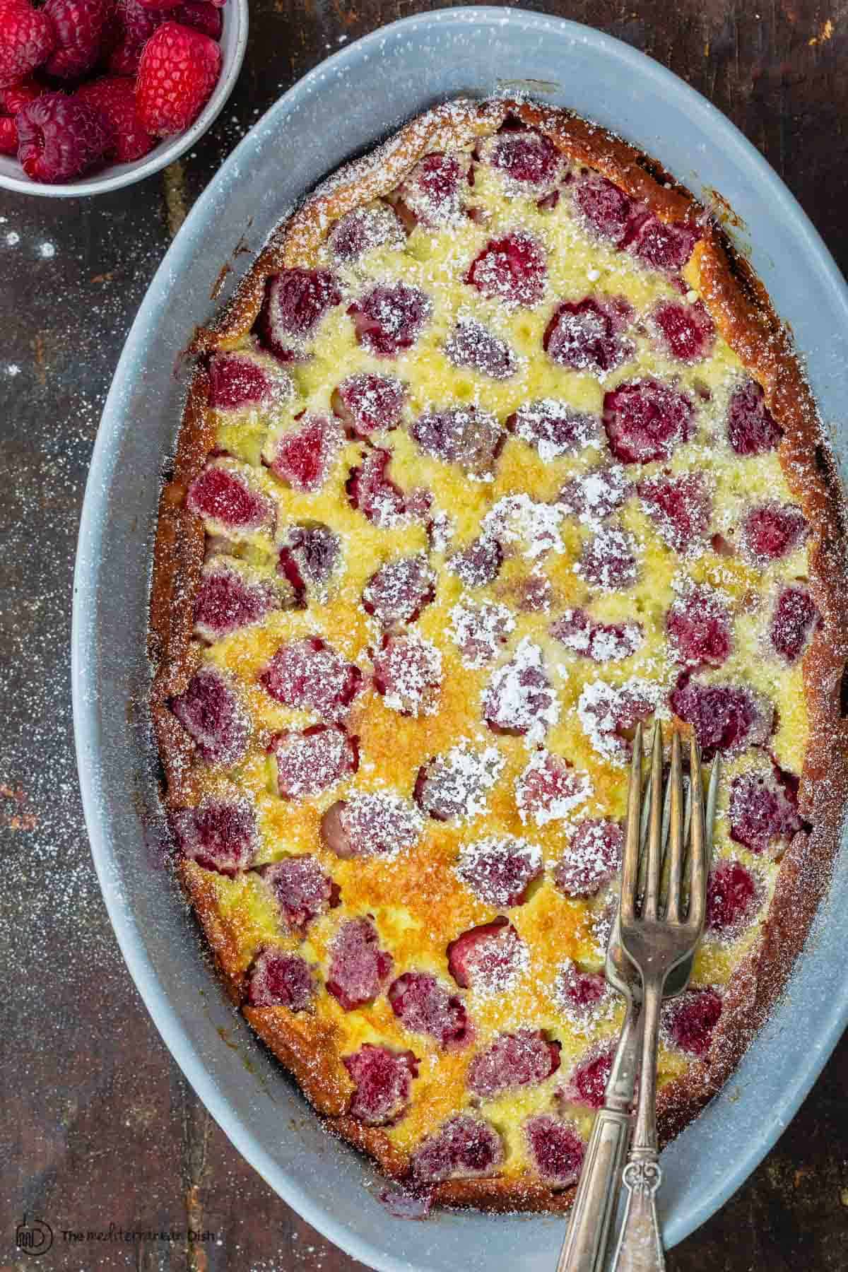 Rasbperry Claufotis in baking dish with a side of fresh berries