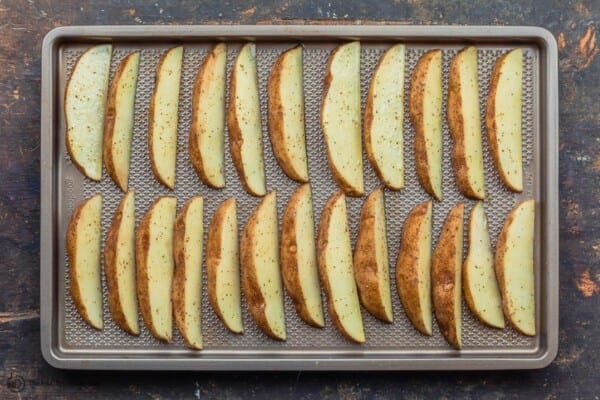 raw potato wedges arranged on sheet pan