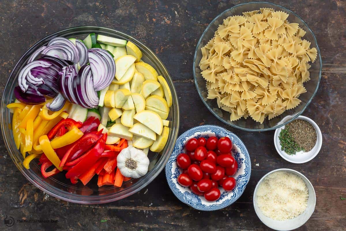ingredients for pasta, including vegetables, tomatoes, pasta, parmesan and spices