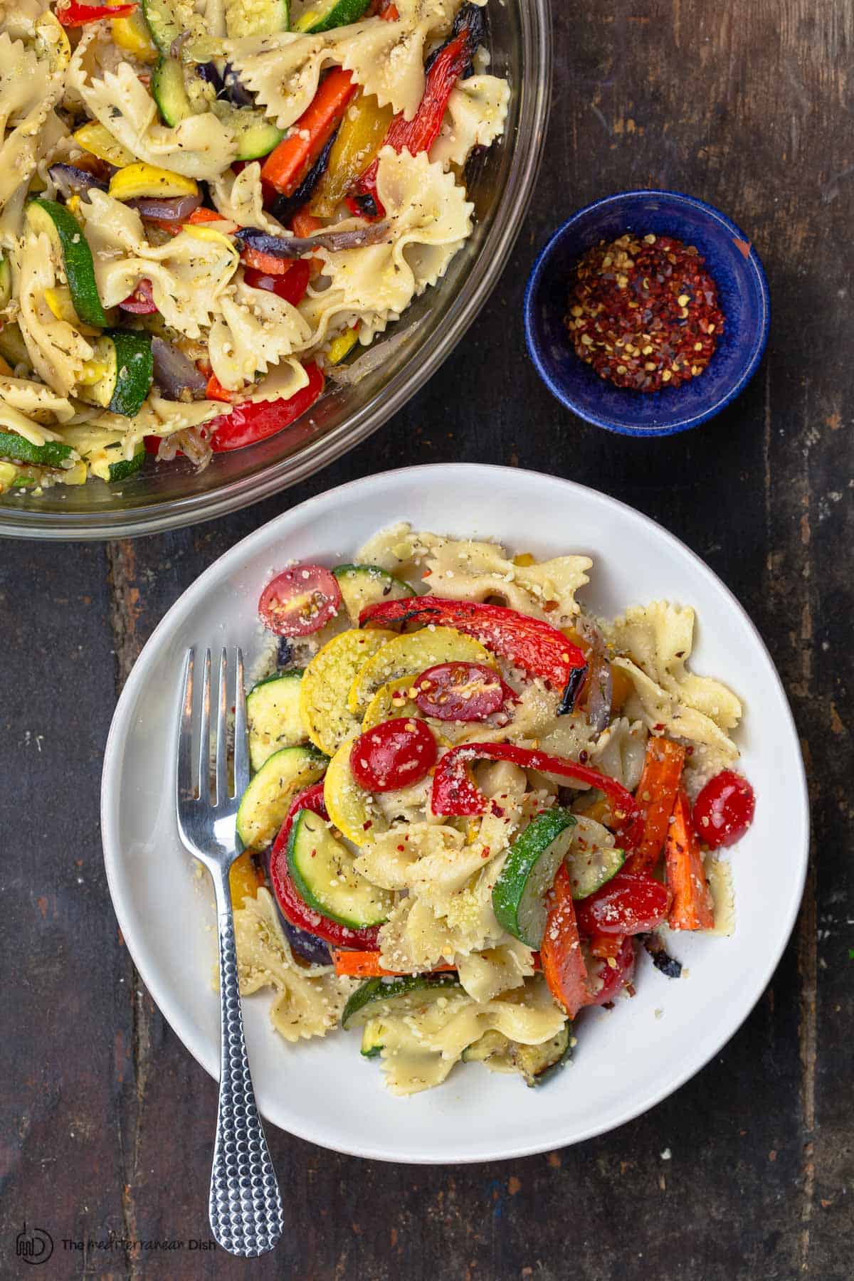 Primavera pasta a side of crushed pepper flakes