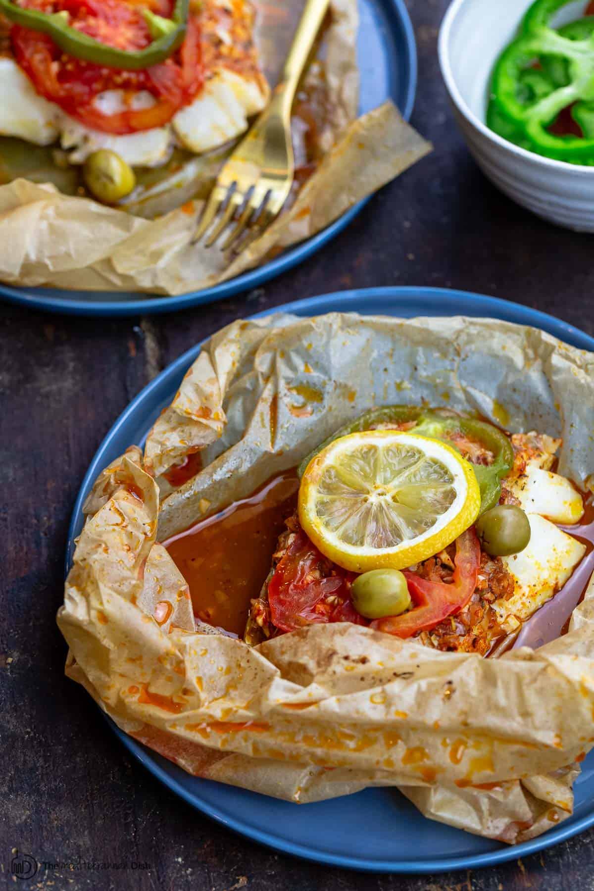 fish en papillote served on plates with side salad