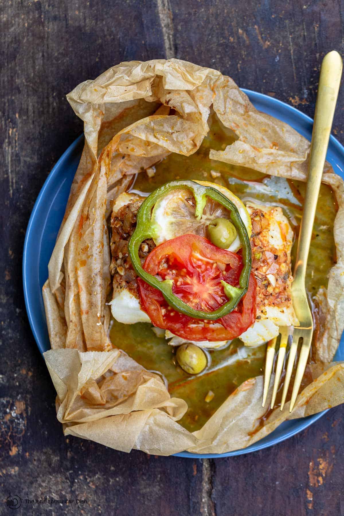 fish en papillote topped with green peppers and tomatoes