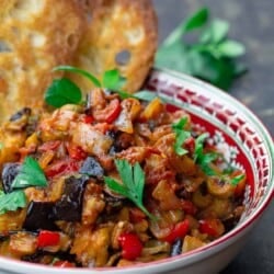 eggplant caponata served in a bowl with toasted ciabatta bread