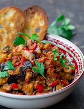 eggplant caponata served in a bowl with toasted ciabatta bread