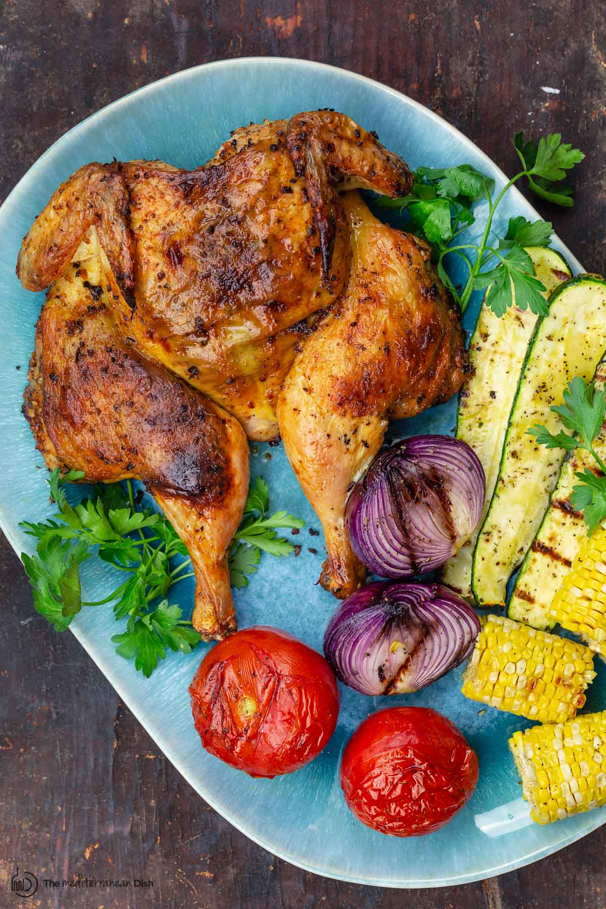 grilled whole chicken with grilled vegetables on a serving platter