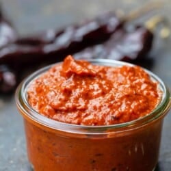 homemade harissa in a small open jar. Dry chiles to the side