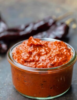 homemade harissa in a small open jar. Dry chiles to the side