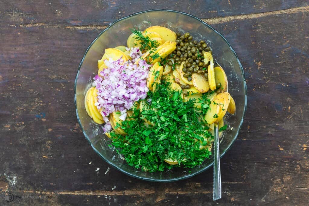 herbs, capers, and onions added to potatoes