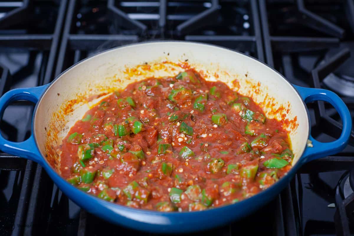 tomatoes are added to the okra in the pan