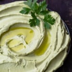 avocado hummus in a bowl with a little extra virign olive oil and a garnish of parsley