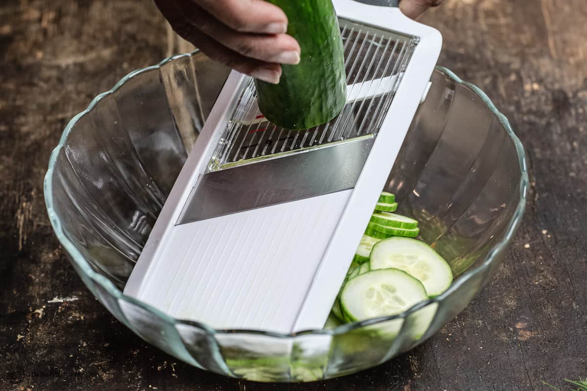 cucumbers being sliced using a mandoline