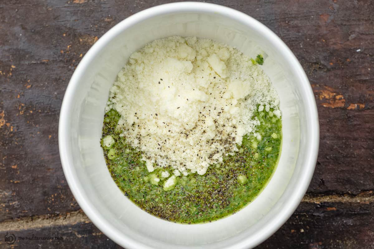 basil mixture with grated parmesan cheese added to a bowl