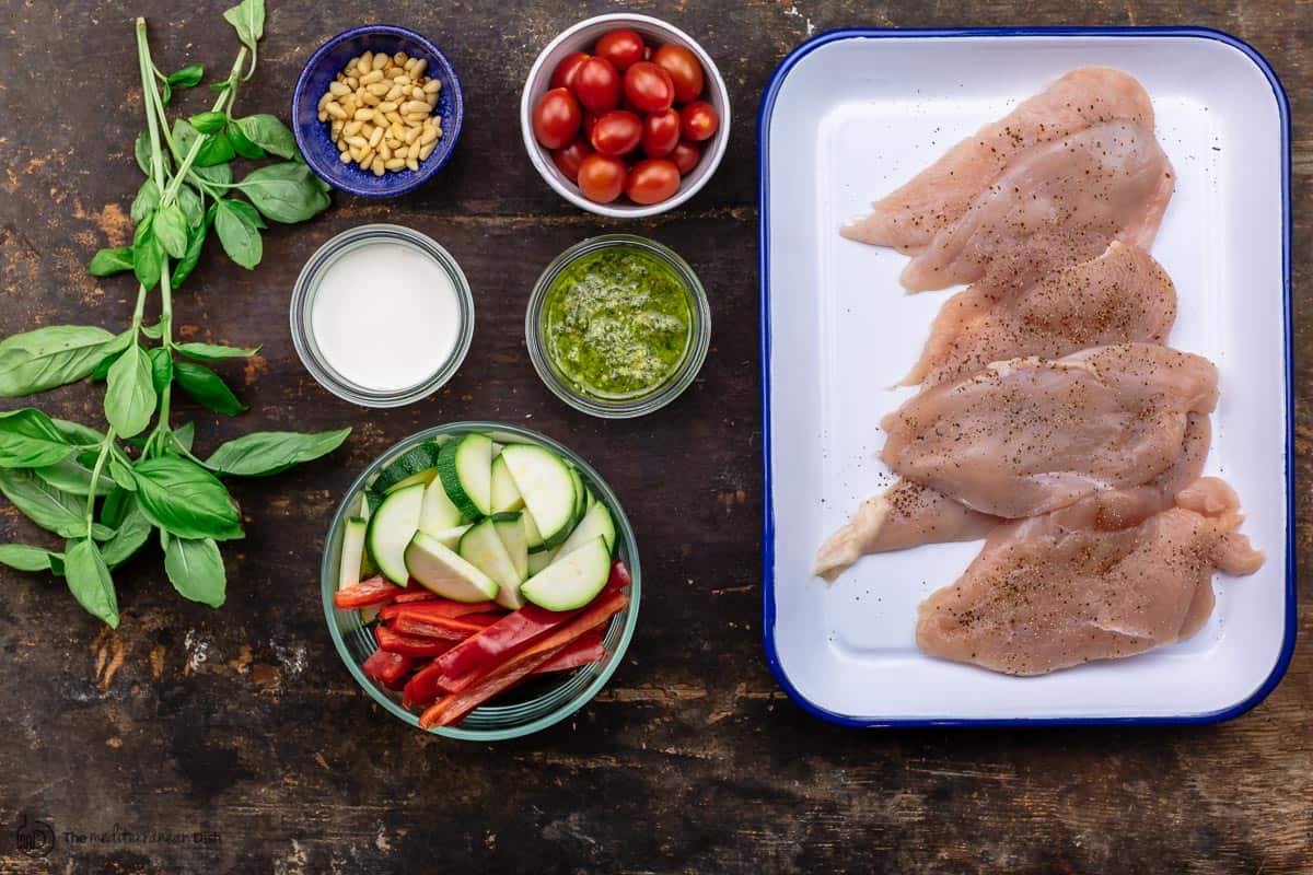 ingredients for chicken pesto. Chicken cutlets, vegetables, cherry tomatoes, pesto, cream, basil and pine nuts