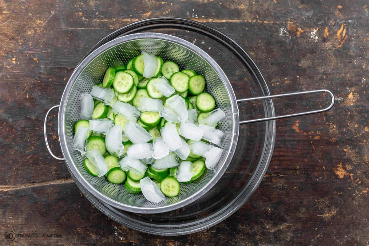 cucumber slices and ice in colander