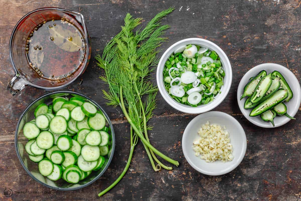 Ingredients for refrigerator pickles. cucumbers, jalapeno, garlic, onions, dill, and brine