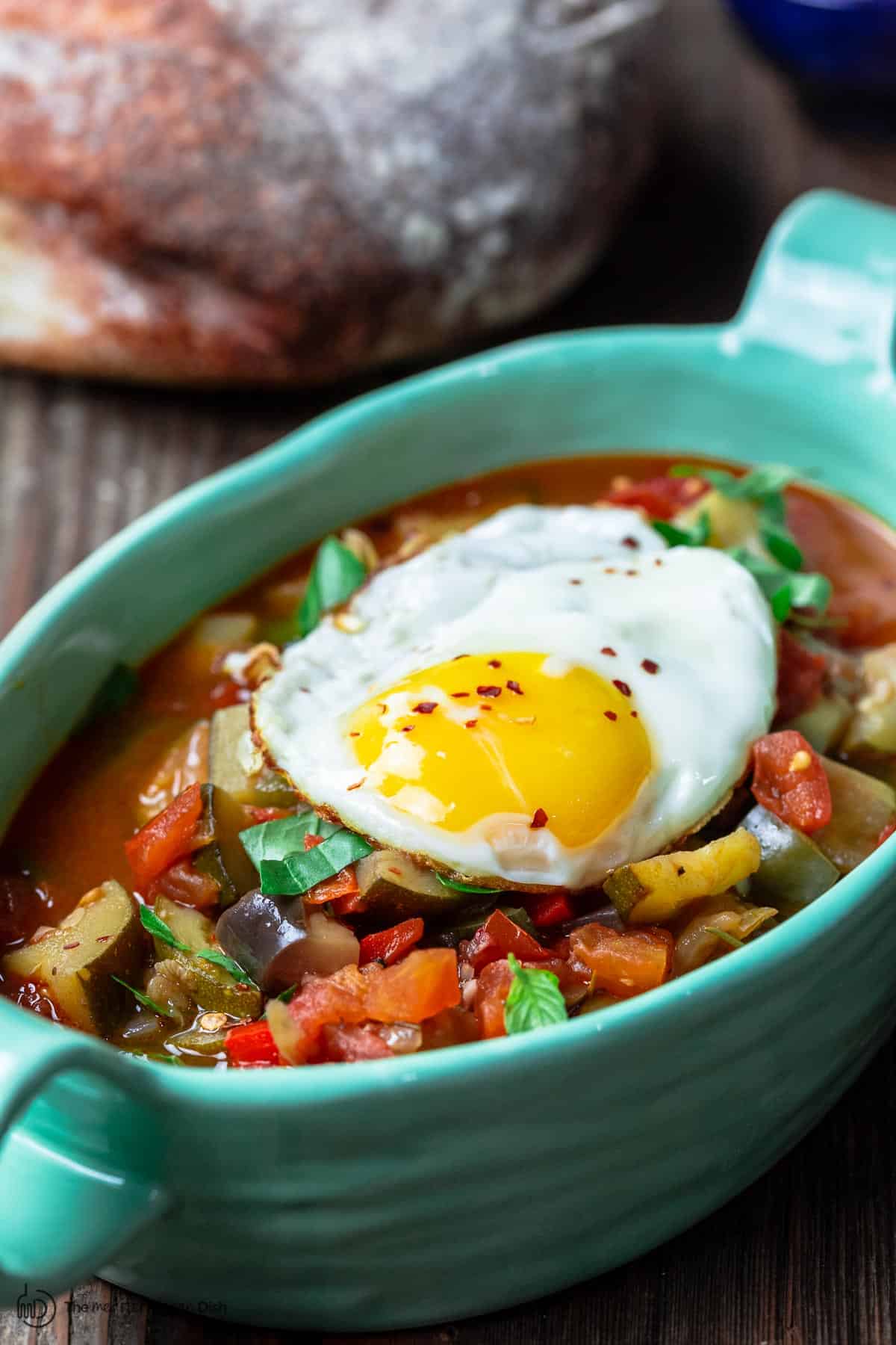 Ratatouille served in a blue pan topped with an egg