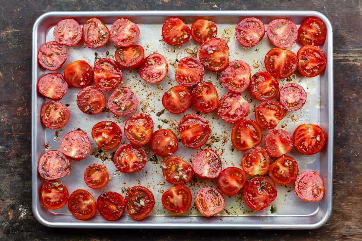 raw tomato halves spread on a sheet pan. Tomato flesh facing up