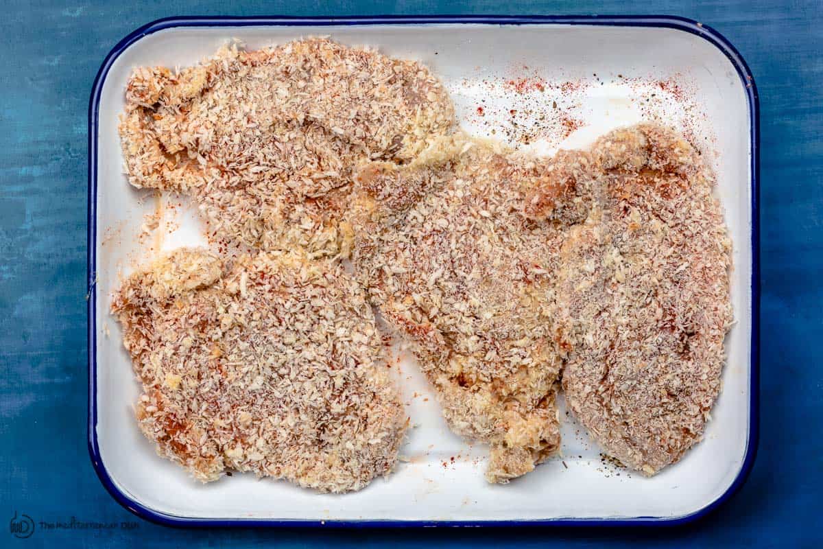 raw chicken breast pieces coated in flour, egg, and panko bread crumbs