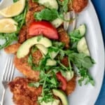 Chicken schnitzel served with arugula salad and lemon juice