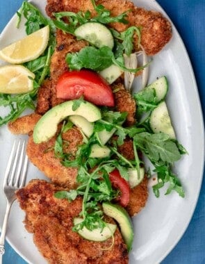 Chicken schnitzel served with arugula salad and lemon juice