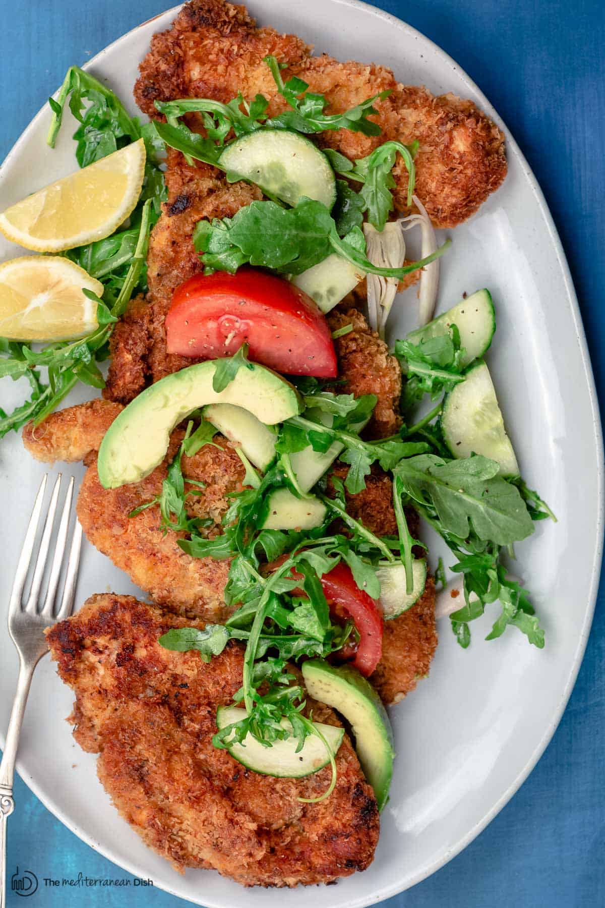 Chicken schnitzel served with arugula salad and lemon juice