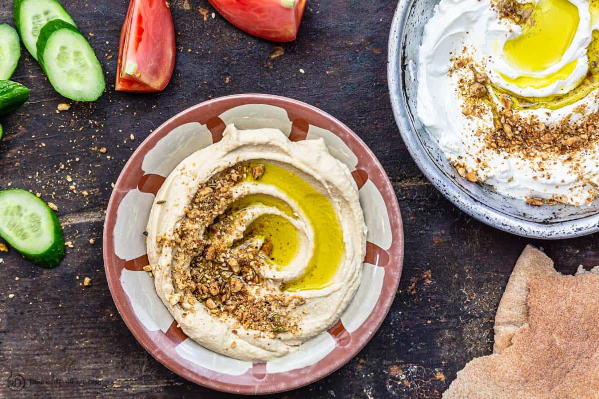 dukkah sprinkled over hummus and labneh with a side of veggies and bread