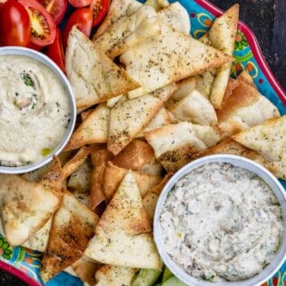 Homemade pita chips as part of mezze platter with two dips and veggies