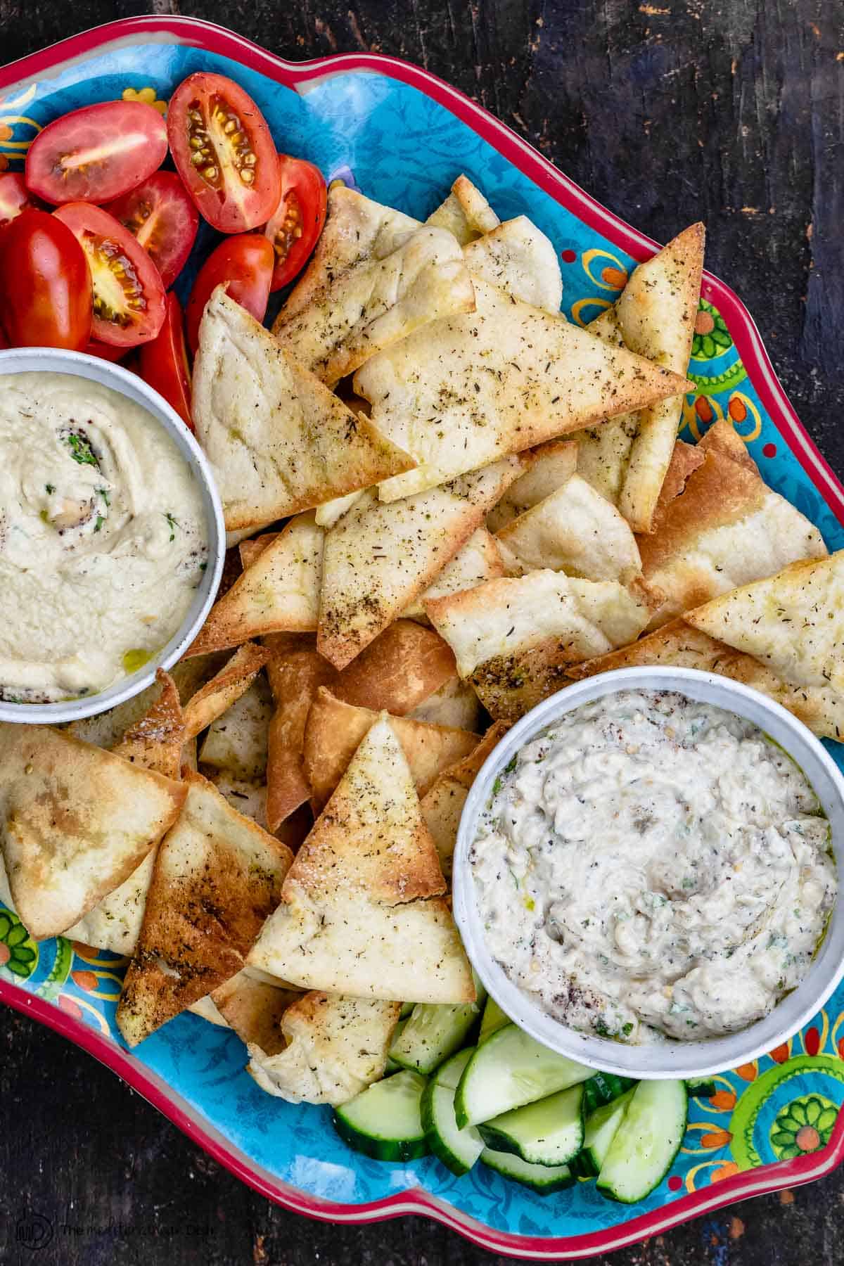 Homemade pita chips as part of mezze platter with two dips and veggies