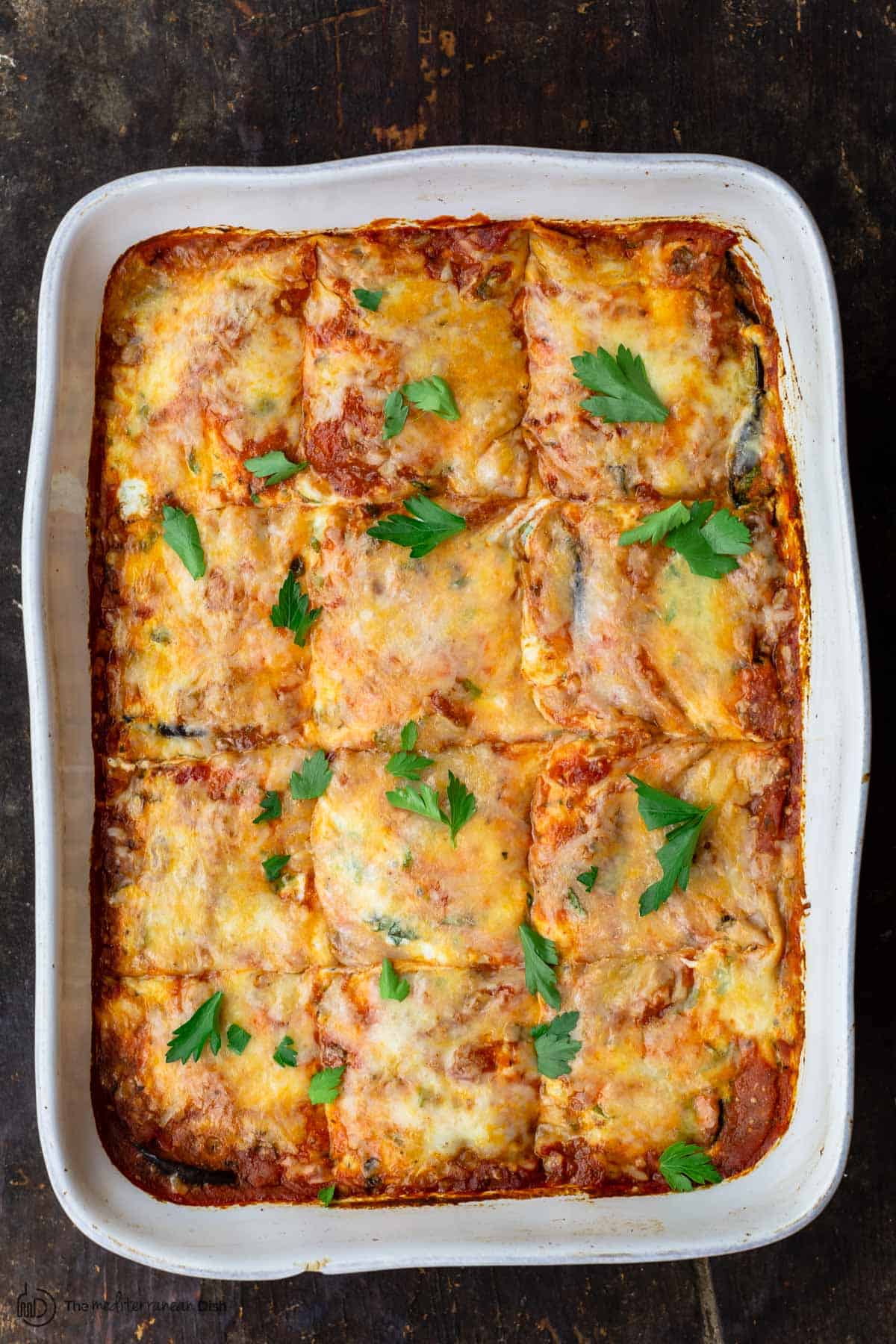 eggplant lasagna in white baking dish with parsley garnish