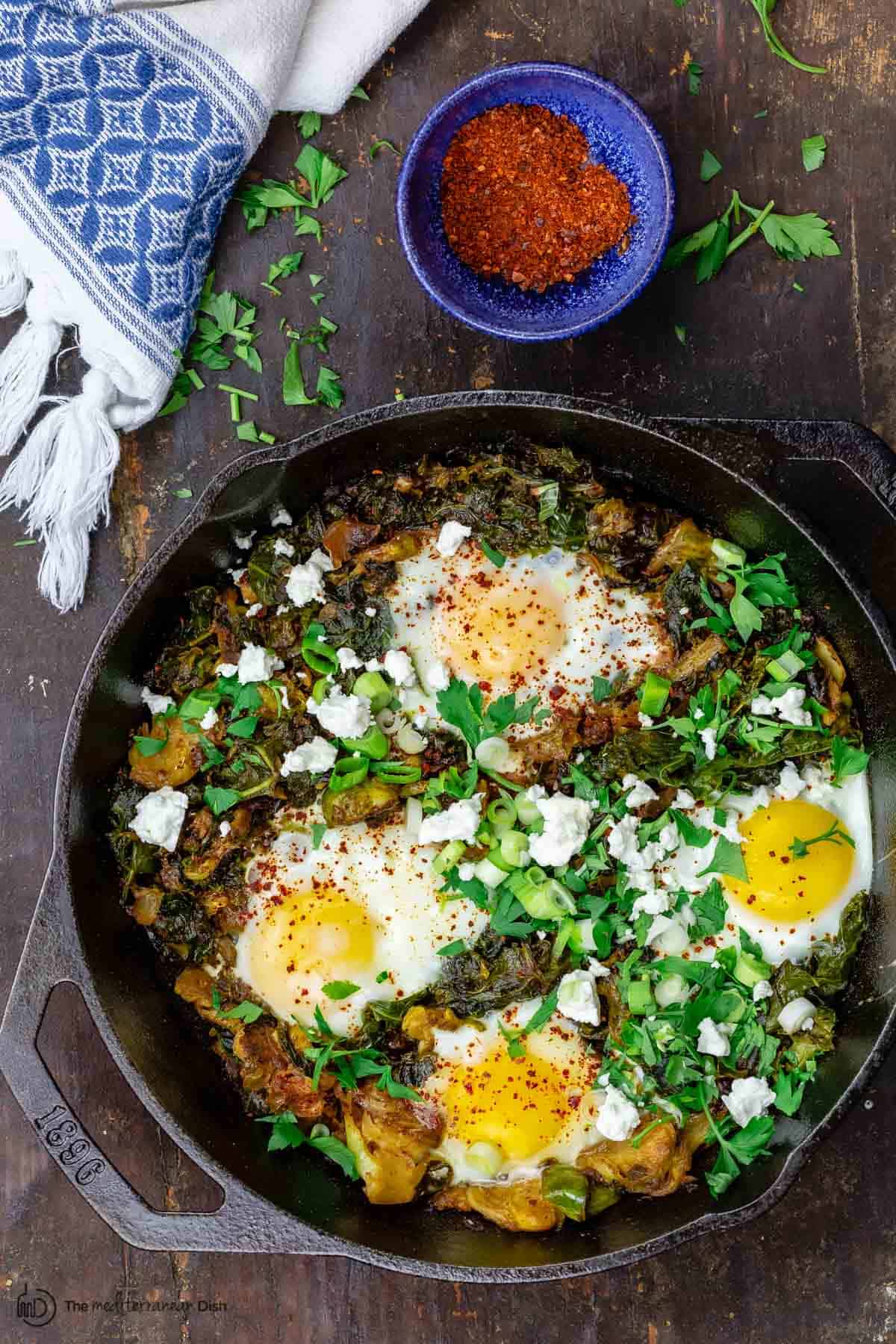 Green shakshuka served with parsley and feta cheese with a side of Aleppo chile pepper flakes 