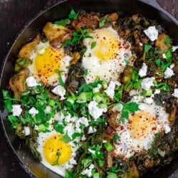 Green shakshuka in skillet with spinach and kale. Topped with feta