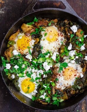 Green shakshuka in skillet with spinach and kale. Topped with feta