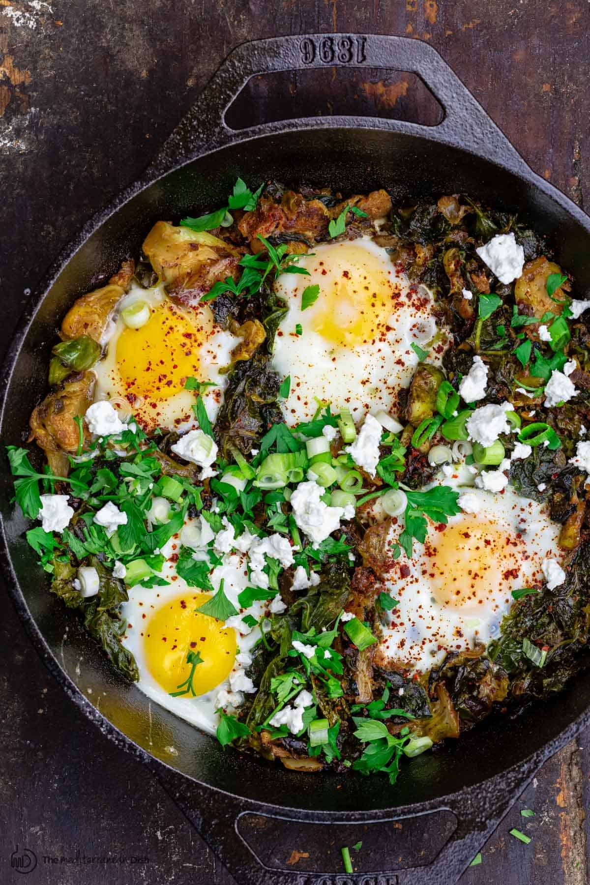 Green shakshuka in skillet with spinach and kale. Topped with feta