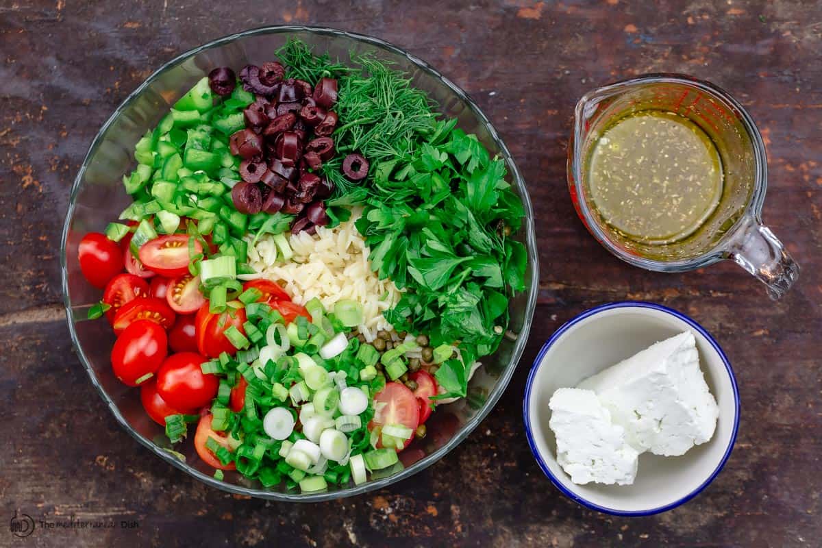 orzo salad ingredients in a large bowl. Feta and dressing to the side.