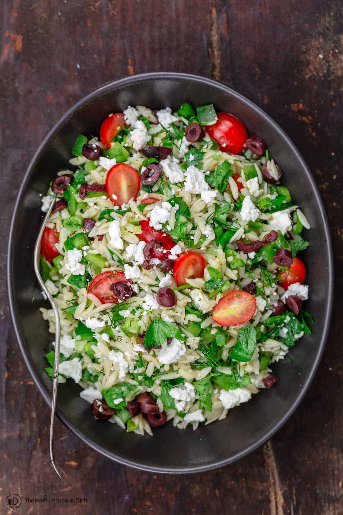 Mediterranean orzo salad in a bowl with a spoon to serve