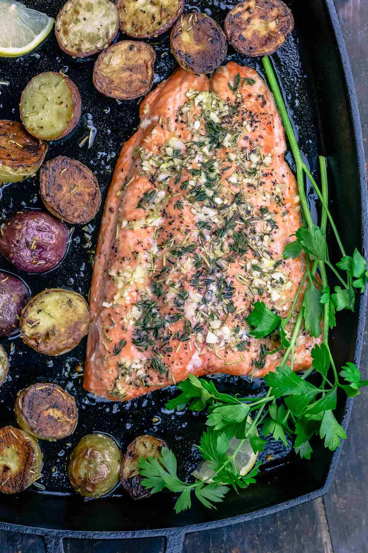 Slow roasted salmon in pan with potatoes and parsley