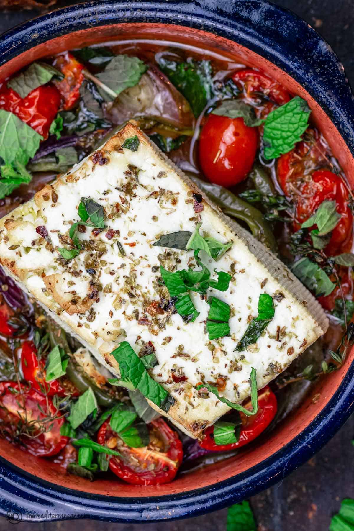 Baked feta with tomatoes, peppers and herbs in a baking dish
