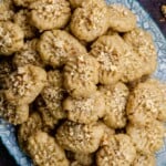 A stack of melomakarona cookies with walnuts on a platter on a platter