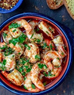 Spanish garlic shrimp with a side of bread and hot red pepper flakes