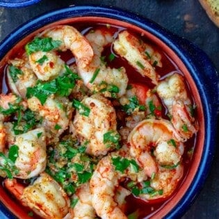 Spanish garlic shrimp with a side of bread and hot red pepper flakes
