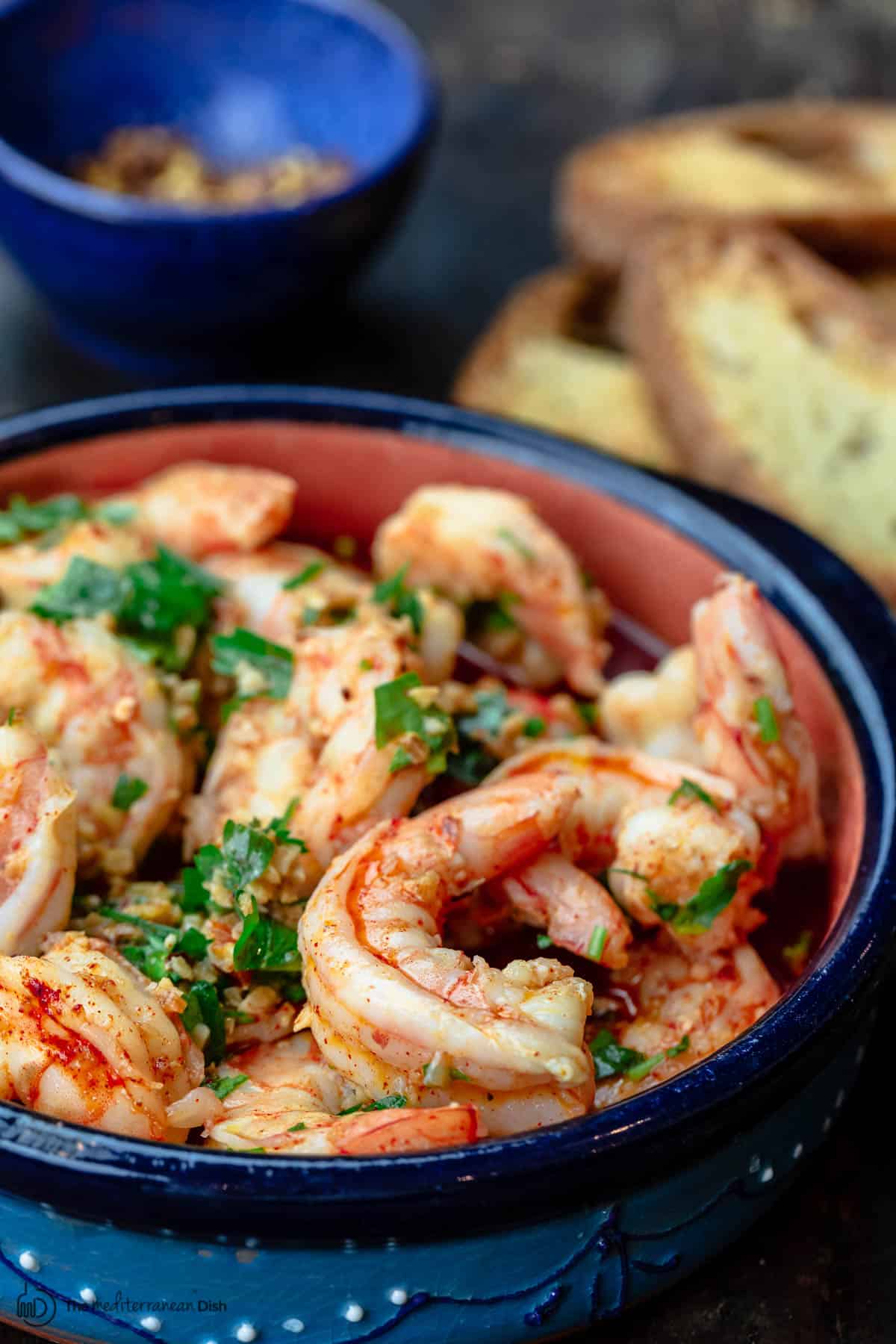 Spanish gambas al ajillo with a side of toasted bread and red pepper flakes
